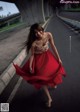 A woman in a red dress is walking down the street.