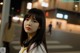 A woman with long black hair standing in the middle of a street.