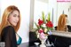 A woman standing in front of a mirror with flowers in a vase.