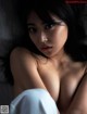 A naked asian woman laying on a bed.