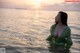 A woman in a green dress is standing in the water.