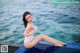 A woman in a white bathing suit sitting on the edge of a swimming pool.