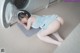 A woman laying on the floor next to a washing machine.