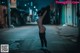 A naked woman standing in the middle of a street at night.