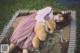 A girl laying on a blanket with a teddy bear.