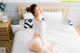 A woman sitting on a bed in a white underwear.