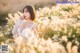 A woman in a white lingerie standing in a field of tall grass.